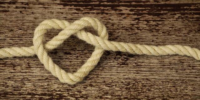 The picture shows a heart made of rope on a wooden board