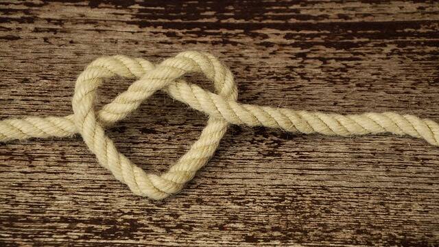 The picture shows a heart made of rope on a wooden board
