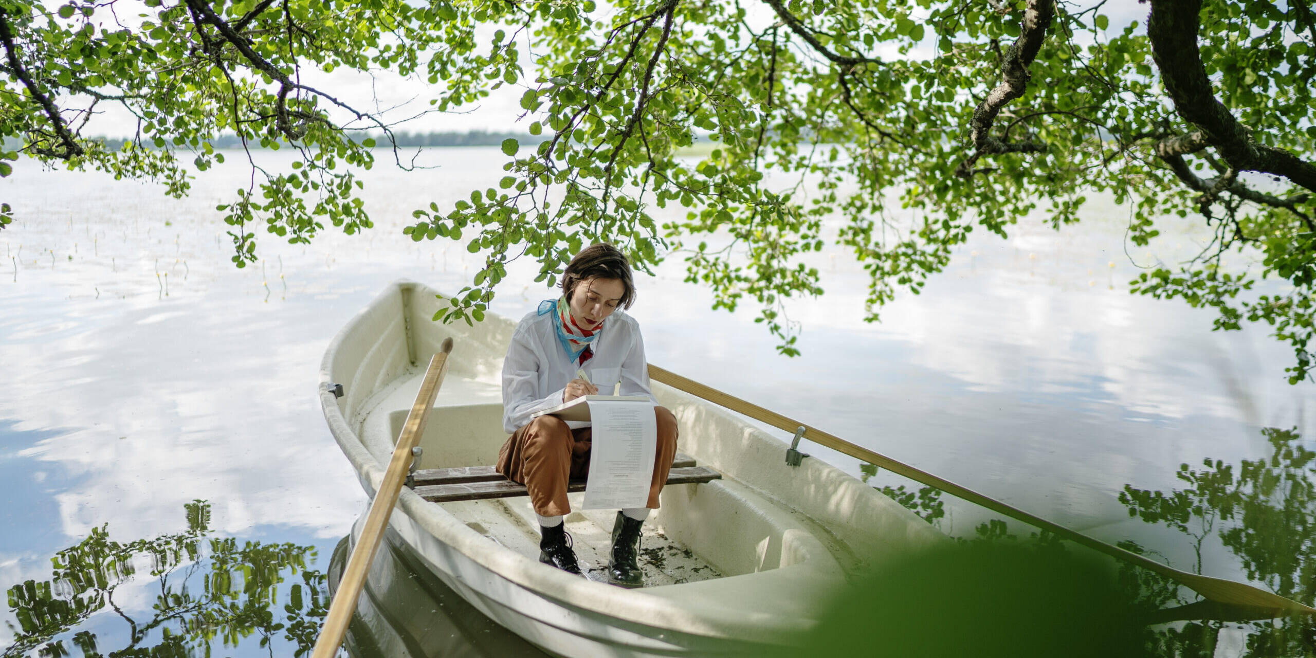 soutuvene ja nainen järvimaisemassa