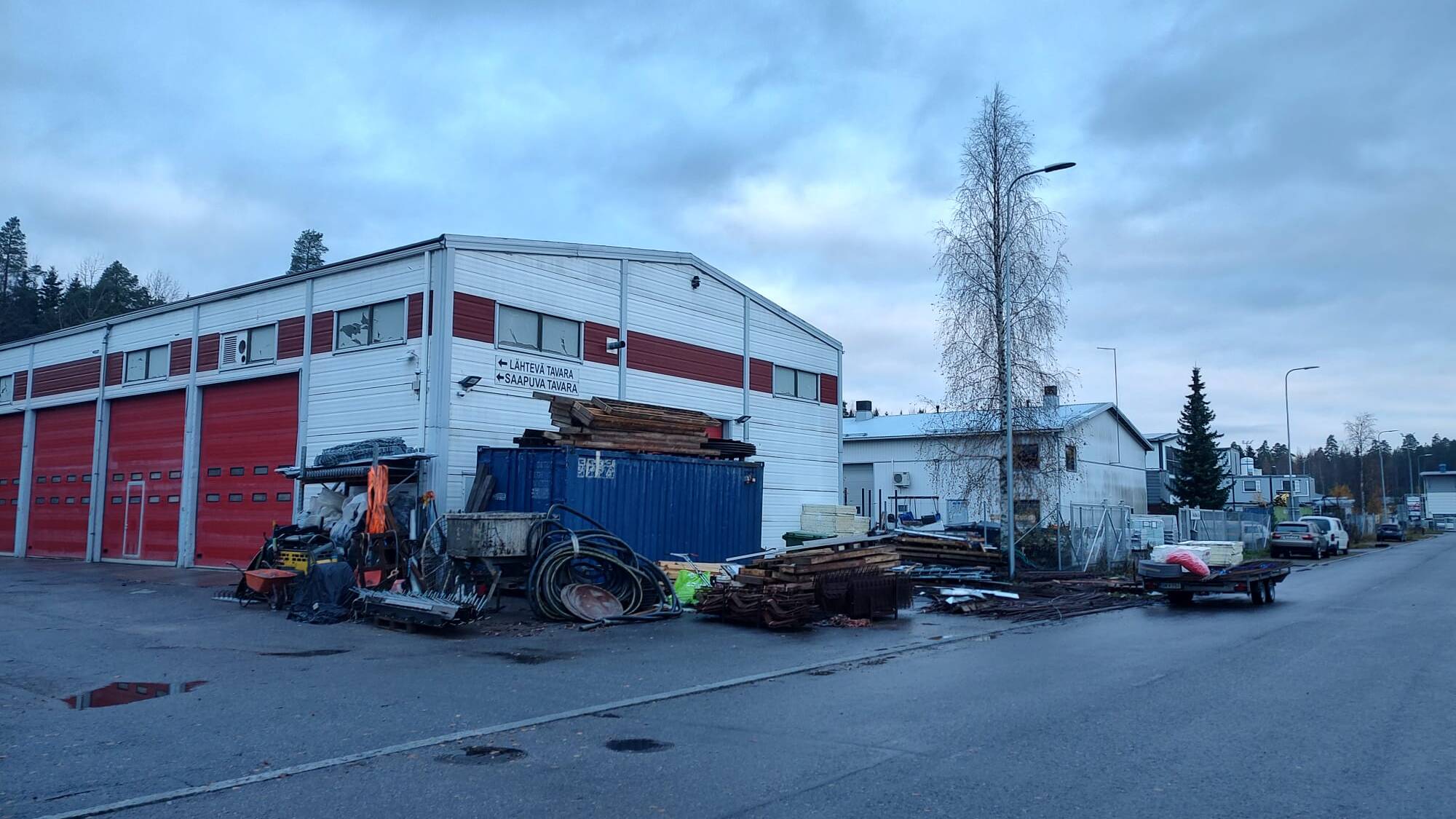 Teollisuusrakennus, jonka edustalla on ajoneuvoja ja työvälineitä.