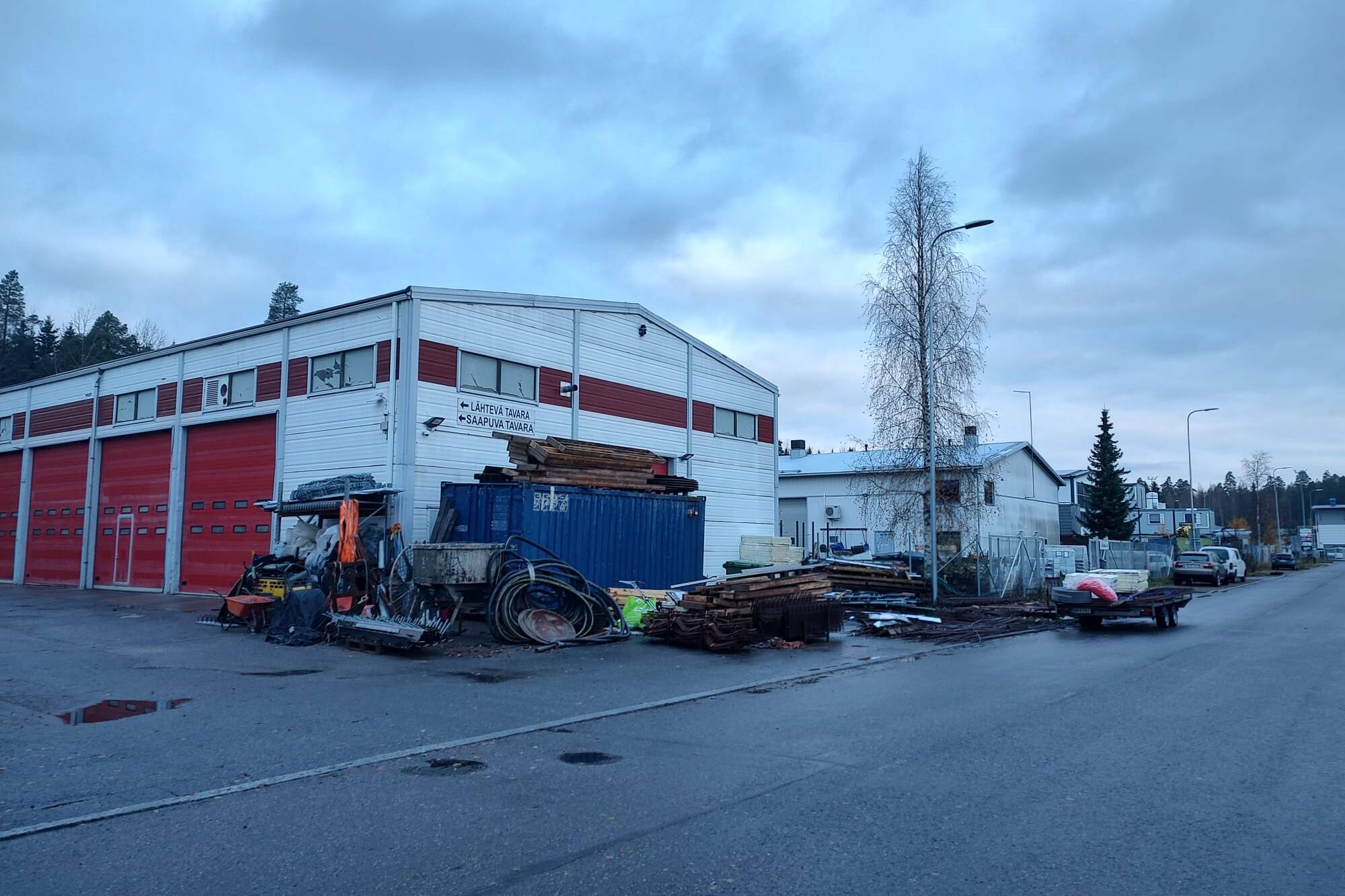 Teollisuusrakennus, jonka edustalla on ajoneuvoja ja työvälineitä.