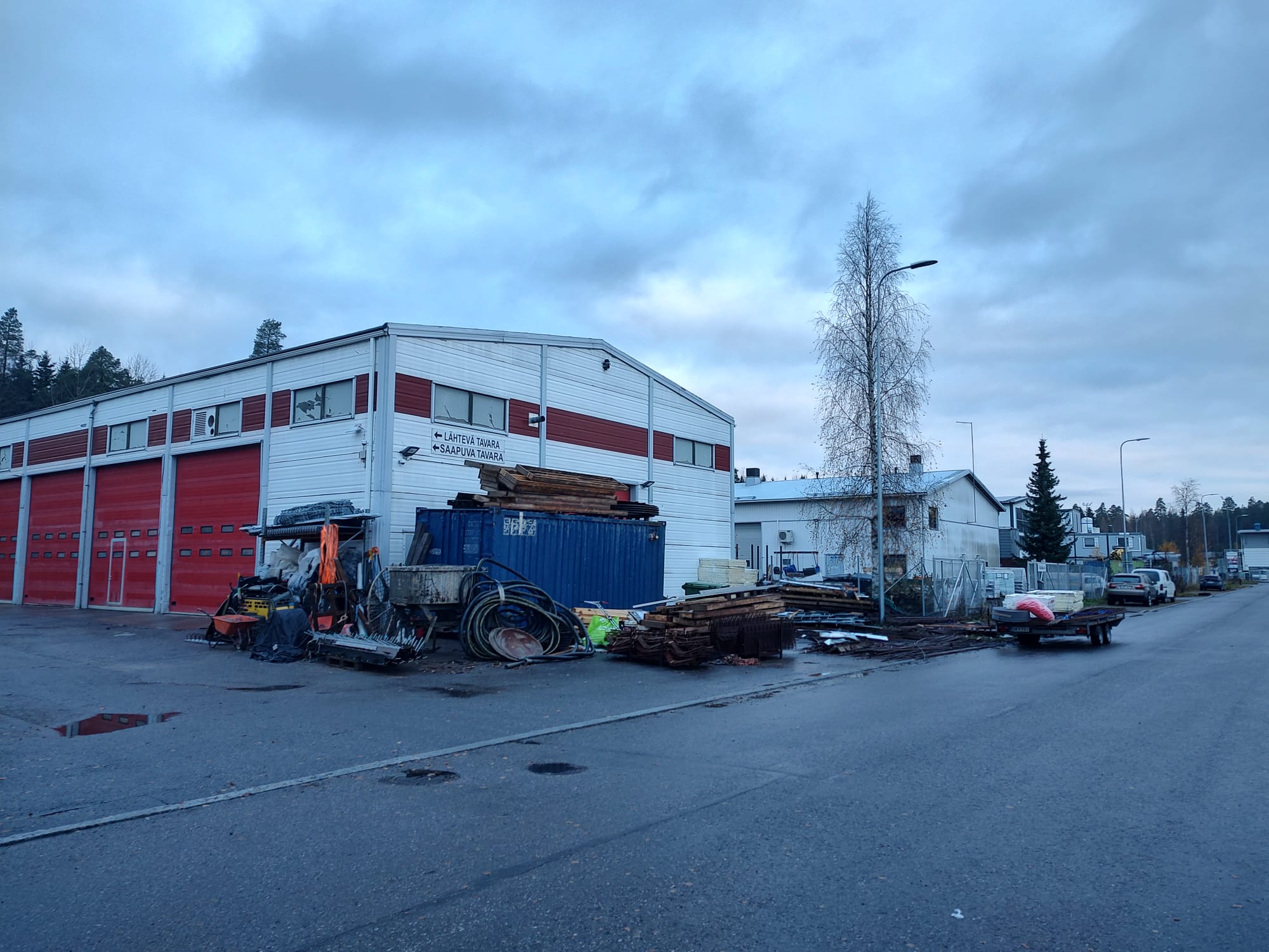 Teollisuusrakennus, jonka edustalla on ajoneuvoja ja työvälineitä.